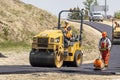 A construction worker using a Cat Tandem Vibratory Roller. Use to compact paving materials
