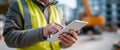 Construction worker using digital tablet on site with blurred heavy machinery and building background Royalty Free Stock Photo
