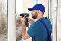 Construction worker using drill while installing window Royalty Free Stock Photo