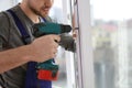 Construction worker using drill while installing window indoors Royalty Free Stock Photo