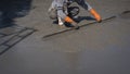 Construction worker using long triangle trowel to plastering cement on the floor