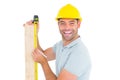 Construction worker using measure tape to mark on plank Royalty Free Stock Photo