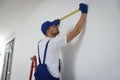 Construction worker using measuring tape in room prepared for renovation Royalty Free Stock Photo