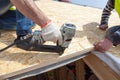 Construction worker using nail gun to nail Oriented Strand Board osb sheeting on roof of a new home.