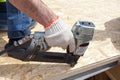 Construction worker using nail gun to nail Oriented Strand Board osb sheeting on roof of a new home.