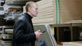 Construction worker using a smartphone to browse materials and prices in a hardware store, carefully selecting the best Royalty Free Stock Photo