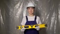 Woman builder in blue overalls and white hard hat helmet with level. Royalty Free Stock Photo