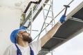 Construction worker in a work attire, protective gloves and a helmet on the head gives a hammer. Work at high altitude. Scaffold Royalty Free Stock Photo