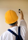 Construction worker works on renovation of apartment. Builder using electric screwdriver and screwing screw out of wall. Royalty Free Stock Photo