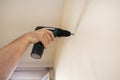 Construction worker works on renovation of apartment. Builder using electric screwdriver and screwing screw out of wall. Royalty Free Stock Photo