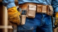 A construction worker with a worn leather tool belt, filled with various tools, and a pair of sturdy work gloves, stands ready for Royalty Free Stock Photo