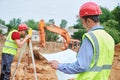 Construction workers on building area. Foreman with blueprint and surveyoor Royalty Free Stock Photo