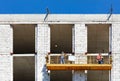 Construction workers climb on a cradle along the facade of a building under construction