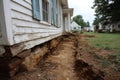 Construction workers digging a trench for foundation repair next to an old house Royalty Free Stock Photo