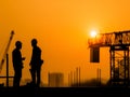 Construction workers discussing project on building site at sunset Royalty Free Stock Photo