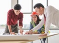 Construction workers , a female architect and two male engineers discussing about the project at office table indoor Royalty Free Stock Photo