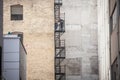 Construction workers fixing Fire escape rusty stairs and ladders, in metal, on a typical North American old brick building.