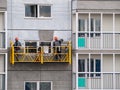 Construction workers installers high-rise workers industrial climbers, painters on the lift paint the facade of the building, comp