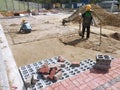 Construction workers installing and arranging precast concrete pavers stone for the car paring area at the construction site.