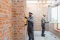 Construction workers installing window, checking brick wall level Royalty Free Stock Photo