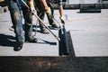 Construction workers insulating rooftop with bituminous membrane. Waterproofing details at construction site. Bituminous membrane