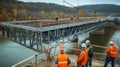Construction Workers Observe Bridge Construction Over a River Royalty Free Stock Photo