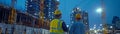 Construction Workers Planning at Night with Tablet in Front of High Rise Building Royalty Free Stock Photo