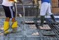Construction workers pour concrete for the execution of a reinforced concrete floor.