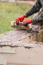 Construction Workers Pouring And Leveling Wet Cement Into Wood Framing