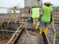 Construction workers pouring wet concrete using concrete bucket from mobile crane Royalty Free Stock Photo