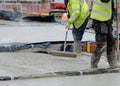 Construction workers pouring wet self levelling concrete screed during ground floor construction of new residential house and