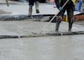 Construction workers pouring wet self levelling concrete screed during ground floor construction of new residential house and