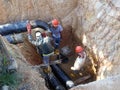 Construction workers risk their lives working inside deep trenches to install underground services pipe.