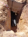 Construction workers risk their lives working inside deep trenches to install underground services pipe.