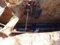 Construction workers risk their lives working inside deep trenches to install underground services pipe.
