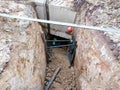 Construction workers risk their lives working inside deep trenches to install underground services pipe.