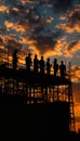 Construction workers silhouetted against a dramatic sunset sky with vibrant clouds Royalty Free Stock Photo