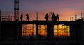 Construction workers silhouetted against a fiery sunset Royalty Free Stock Photo