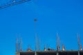 Construction workers on construction site with crane lifting materials against clear blue sky, demonstrating teamwork Royalty Free Stock Photo