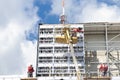 Construction workers on construction site making external cladding structure on a building facade wall Royalty Free Stock Photo