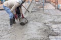 Construction workers spreading fresh poured concrete mix for house building