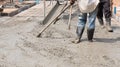 Construction workers spreading fresh poured concrete mix for house building