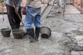 Construction workers spreading freshly poured concrete mix for building