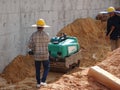 Construction workers are using the baby compactor to level and compact the soil at the construction site.