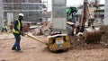 Construction workers are using the baby compactor to level and compact the soil at the construction site.