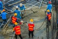 Construction workers using a concrete vibrator gasoline engine type at the construction site to compact the liquid concrete in r