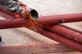 Construction workers are using grinding machines on large steel pipes. Used as a roof pole. Sparking while working Red painted Royalty Free Stock Photo