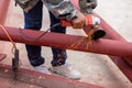 Construction workers are using grinding machines on large steel pipes. Used as a roof pole. Sparking while working Red painted Royalty Free Stock Photo