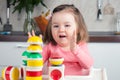 Construction a 2 year old girl with long hair plays with a designer at home, builds towers, rejoices at successes