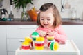 Construction a 2 year old girl with long hair plays with a designer at home, builds towers, rejoices at successes. Royalty Free Stock Photo